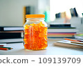 A jar of Gummy Vitamins is on the student's desk. The concept of taking vitamins to maintain child health while studying 109139709