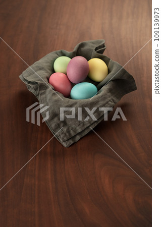 Easter eggs in a bowl with napkin on walnut wood table with copy space Easter eggs in a bowl with napkin on walnut wood table with copy space 109139973