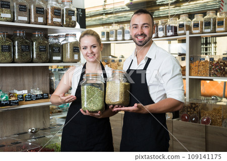Pair of charming sellers with aprons at store of herbs and ecological food 109141175