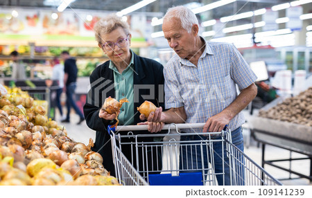 Mature spouses chooses potato in vegetable section of supermarket 109141239