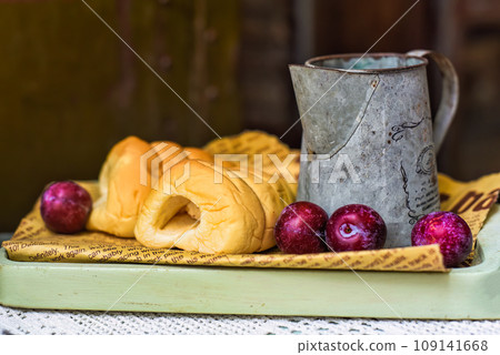 whipped cream tubes with cup and plums on wooven cloth on black background whipped cream tubes with cup and plums on wooven cloth on black background 109141668