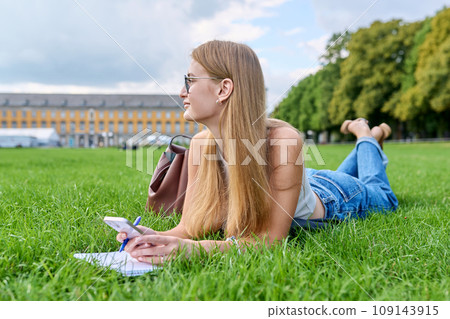 Young student girl lying on grass, educational building background 109143915