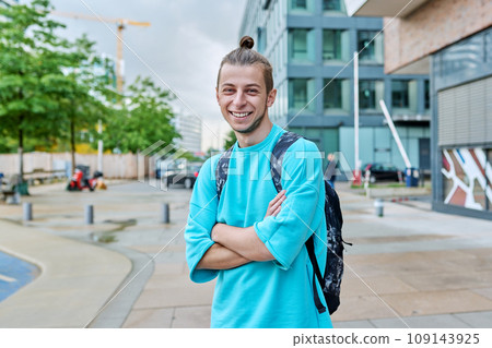 Happy young guy with backpack with crossed arms outdoor, city background 109143925