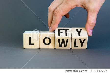 Lofty or lowly symbol. Concept words Lofty Lowly on wooden block. Beautiful grey table grey background. Businessman hand. Business lofty or lowly concept. Copy space. Lofty or lowly symbol. Concept words Lofty Lowly on wooden block. Beautiful grey table grey background. Businessman hand. Business lofty or lowly concept. Copy space. 109147724