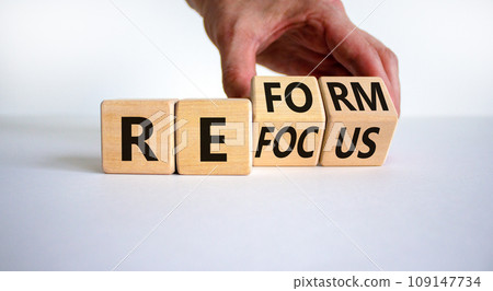 Refocus and reform symbol. Businessman turns cubes and changes the word 'refocus' to 'reform'. Beautiful white table, white background. Business refocus and reform concept. Copy space. Refocus and reform symbol. Businessman turns cubes and changes the word 'refocus' to 'reform'. Beautiful white table, white background. Business refocus and reform concept. Copy space. 109147734