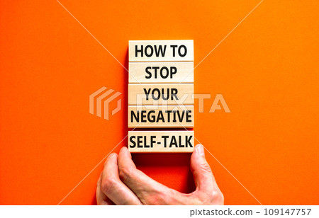 Stop negative self-talk symbol. Concept words How to stop your negative self-talk on wooden block. Psychologist hand. Beautiful orange background. Psychological negative self-talk concept. Copy space Stop negative self-talk symbol. Concept words How to stop your negative self-talk on wooden block. Psychologist hand. Beautiful orange background. Psychological negative self-talk concept. Copy space 109147757