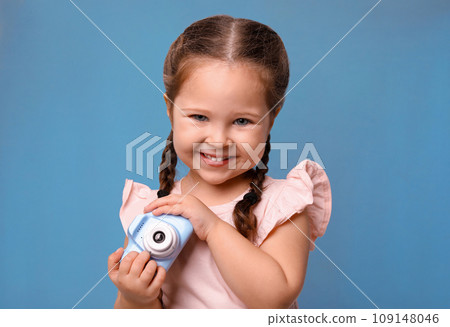 Little photographer with toy camera on light blue background 109148046