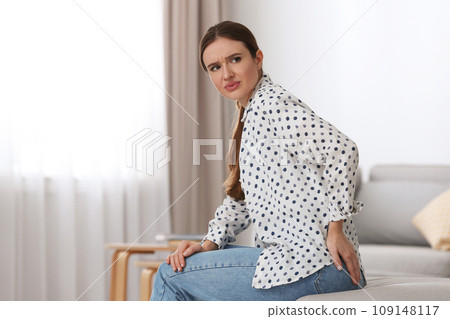 Young woman suffering from hemorrhoid at home. Space for text 109148117