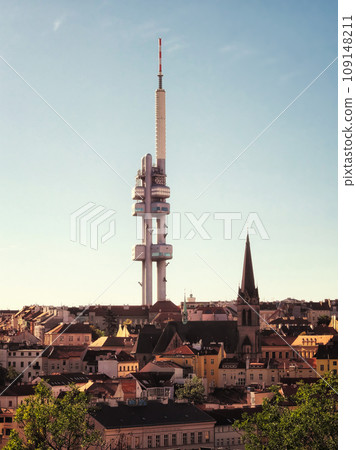 The image shows the Zizkov Television Tower in Prague, Czech Republic. Its a tall, white structure with multiple levels and a red and white antenna on top. 109148211