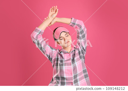 Beautiful woman wearing sleeping mask on pink background. Bedtime 109148212