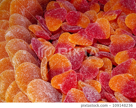 A close-up of orange and red gummy candies in the shape of hearts, covered in sugar crystals. A close-up of orange and red gummy candies in the shape of hearts, covered in sugar crystals. 109148236