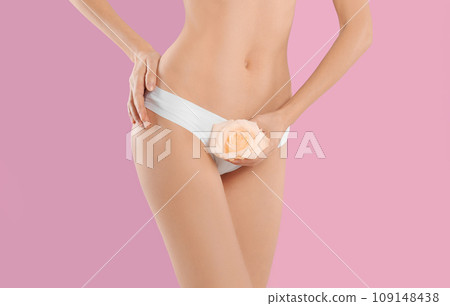 Woman with flower showing smooth skin after bikini epilation on pink background, closeup Woman with flower showing smooth skin after bikini epilation on pink background, closeup 109148438