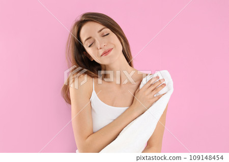 Young woman wiping body with towel on light pink background 109148454