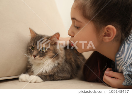 Cute little girl with cat on sofa at home. First pet 109148457