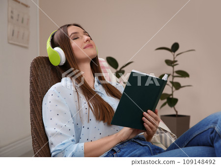 Woman listening to audiobook in chair at home 109148492