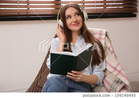 Woman listening to audiobook in chair at home 109148493