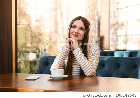 Woman listening to audiobook at table in cafe 109148502