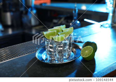 Mexican Tequila shots with lime slices on bar counter Mexican Tequila shots with lime slices on bar counter 109148544