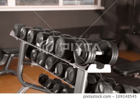 Dumbbells on rack in gym. Modern sport equipment Dumbbells on rack in gym. Modern sport equipment 109148545