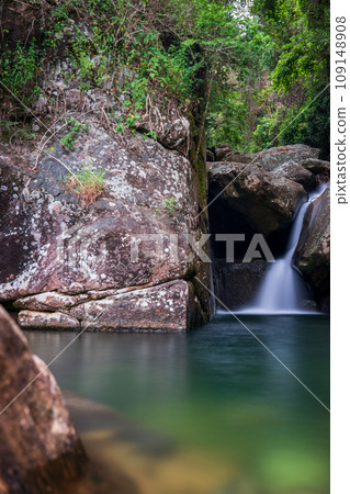 Silky Water Flowing Over Rocks Forming Vibrant Green Pond in Lush Forest Silky Water Flowing Over Rocks Forming Vibrant Green Pond in Lush Forest 109148908