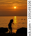 Silhouette of a little girl playing on the seashore during sunset 109149106