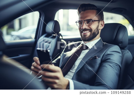 Businessman inside of a car looking at the mobile phone or using mobile phone Businessman inside of a car looking at the mobile phone or using mobile phone 109149288