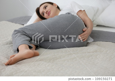 Young woman suffering from hemorrhoid on bed at home, focus on hand Young woman suffering from hemorrhoid on bed at home, focus on hand 109150271