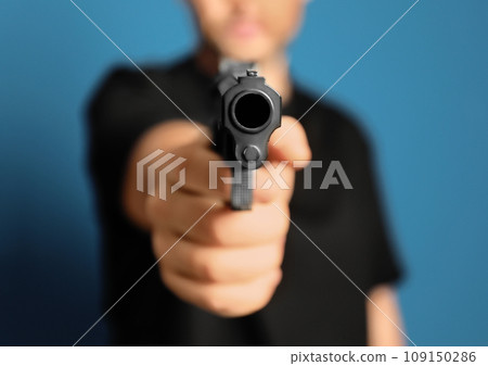 Man holding gun on blue background, closeup Man holding gun on blue background, closeup 109150286