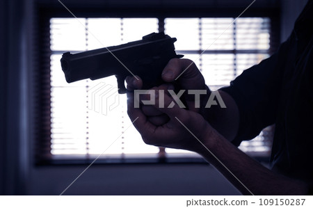 Man holding gun near window indoors, closeup Man holding gun near window indoors, closeup 109150287