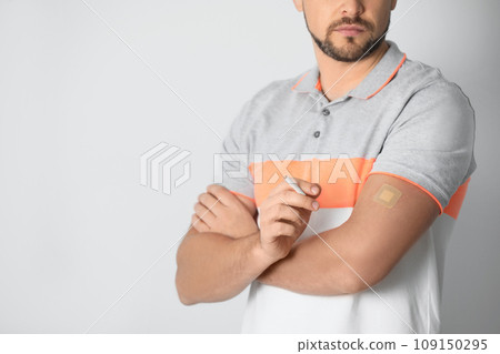 Man with nicotine patch and cigarette on light grey background, closeup 109150295