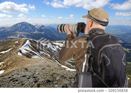 man tourist photographer with a backpack photographs the beauty of nature in the mountains 109150856