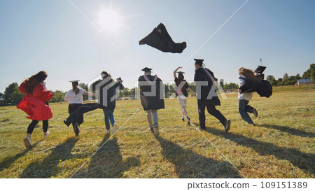 Happy graduates run in and take off their robes. The concept of graduation. 109151389