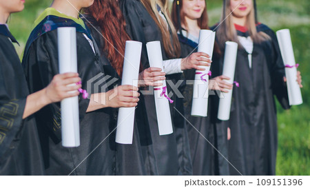 Scrolls of diplomas in the hands of a group of graduates. Scrolls of diplomas in the hands of a group of graduates. 109151396