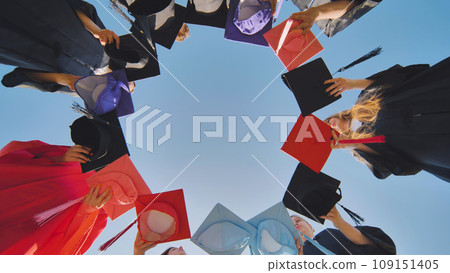 College graduates make a circle shape out of their colorful hats. 109151405