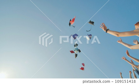 Graduates tossing multicolored hats against a blue sky. Graduates tossing multicolored hats against a blue sky. 109151418