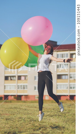 A girl happily poses with large with colorful balloons in the city. A girl happily poses with large with colorful balloons in the city. 109151443
