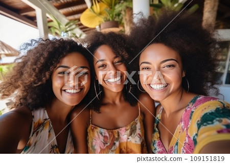 Three African American young women taking selfie on summer vacation. Beautiful diverse girls in colorful sundresses laughing happily. Happy millennial female friends having fun together outdoors. Three African American young women taking selfie on summer vacation. Beautiful diverse girls in colorful sundresses laughing happily. Happy millennial female friends having fun together outdoors. 109151819