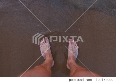 Male feet on sea sand. 109152000