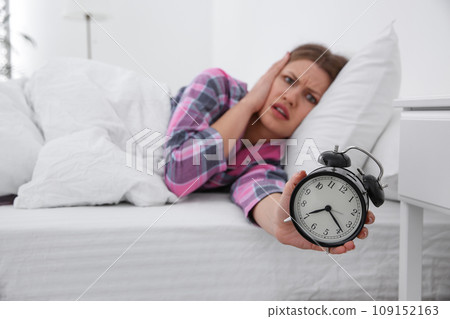Emotional young woman with alarm clock at home in morning, focus on hand Emotional young woman with alarm clock at home in morning, focus on hand 109152163