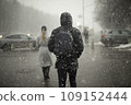 Snow in city. Heavy snow is falling outside. Blurry silhouettes of people in blizzard. 109152444
