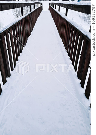 Snow-covered wooden bridge in park on winter day. Snow-covered wooden bridge in park on winter day. 109152797