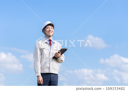 一個穿著工作服的男人拿著平板電腦終端 109153482