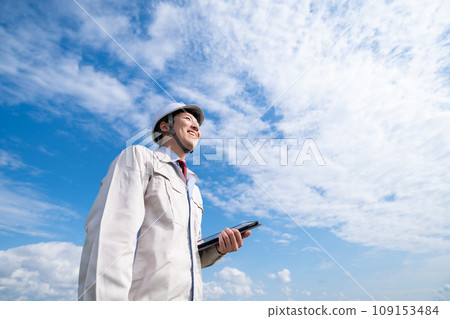 一個穿著工作服的男人拿著平板電腦終端 109153484