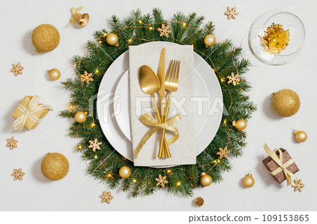 Festive table setting with Christmas wreath and golden decorations on white background. Preparation for Christmas dinner. Top view, flat lay. 109153865