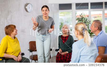 Young girl conducting language club for group of older adults 109154376