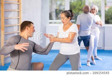 Old woman twisting her opponent's arm during self-defense classes 109154545