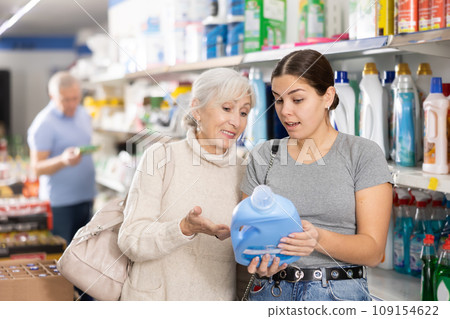 Young and mature woman shopping in supermarket, chooses plastic bottle of household detergent 109154622