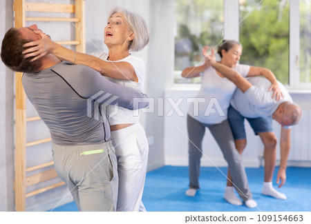 Elderly woman delivers painful blow to her eyes during a self-defense course in gym 109154663