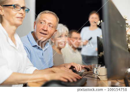 Senior man attending computer class under guidance of female teacher Senior man attending computer class under guidance of female teacher 109154758