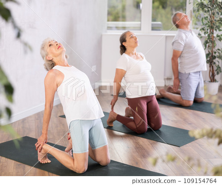 Elderly woman performs camel pose, Ushtrasana to improve mobility of spine and stretch muscles 109154764
